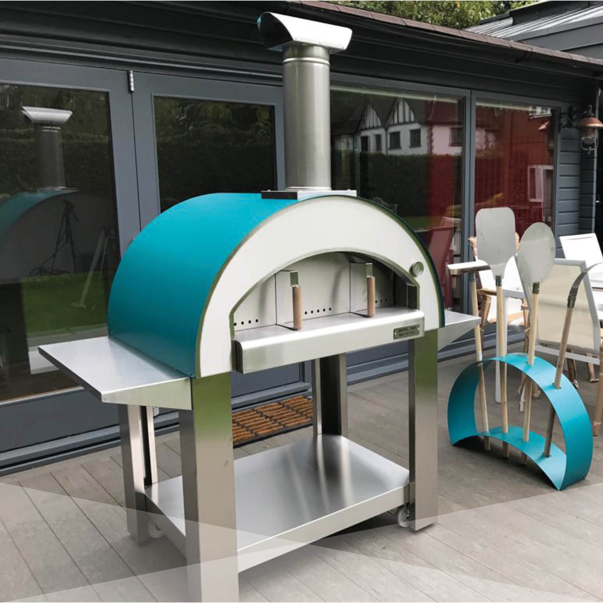 Grande Image Wood fired BBQ in stainless steel with a teal finish, accompanied by a utensil stand in teal.