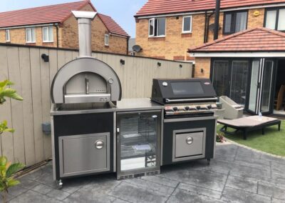 Outdoor Kitchen, with woodfired pizza oven, BBQ unit with lift up lid, central fridge and two storage areas.